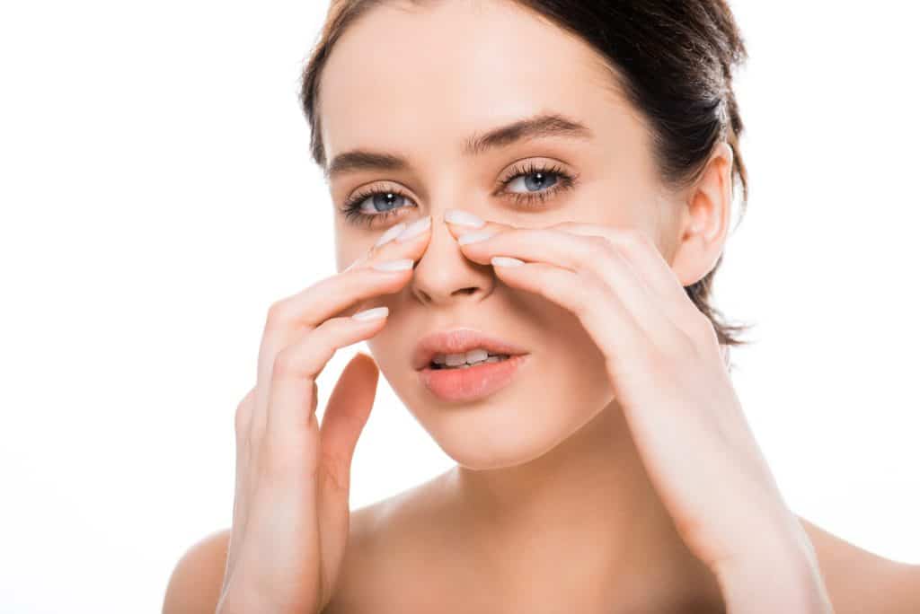 Woman Touching Nose After Rhinoplasty Surgery - Ambrosia Clinic